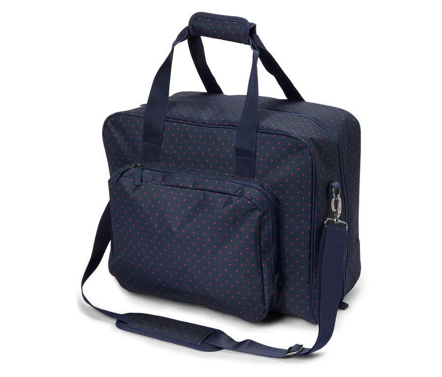 Un sac bleu marine avec un motif de cœurs rouges et des bretelles bleu marine reposant sur une surface blanche.