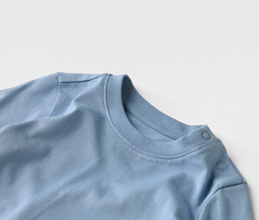Vue détaillée d'un t-shirt bleu clair avec encolure ras du cou et patte de boutonnage à l'épaule.