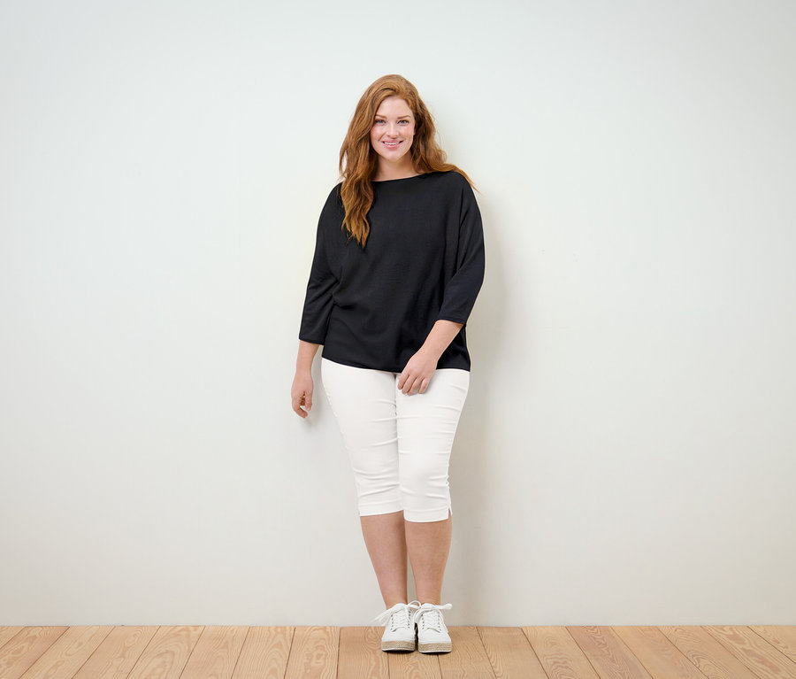 Femme debout en pantalon 3/4-Stretchhose blanc.