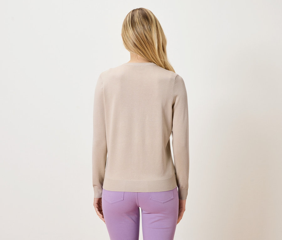Vue arrière d'une femme blonde portant un pull beige et un pantalon violet.
