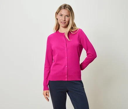 Femme portant un cardigan rose et un pantalon bleu.