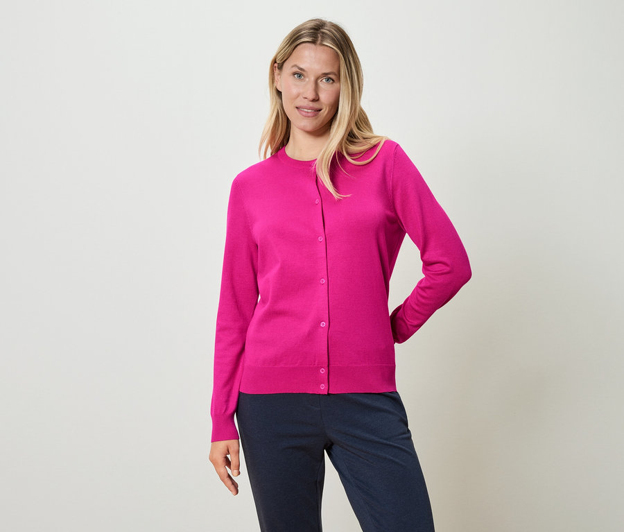 Femme portant un cardigan rose et un pantalon bleu.