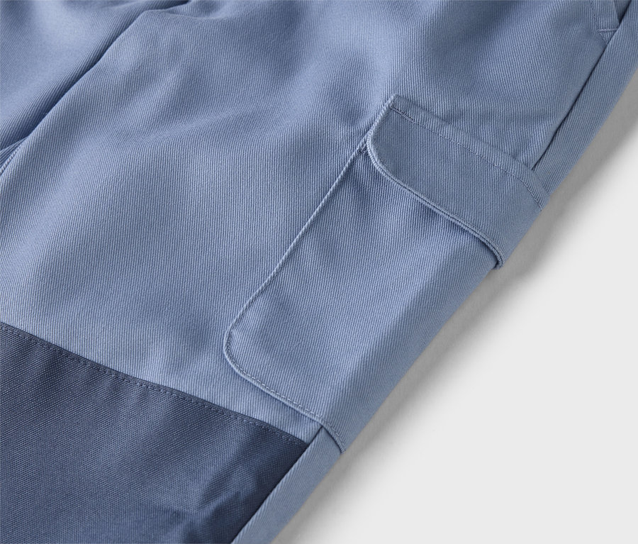 Gros plan d'un pantalon bleu clair avec une poche plaquée sur la jambe et un empiècement bleu marine en bas de la jambe.