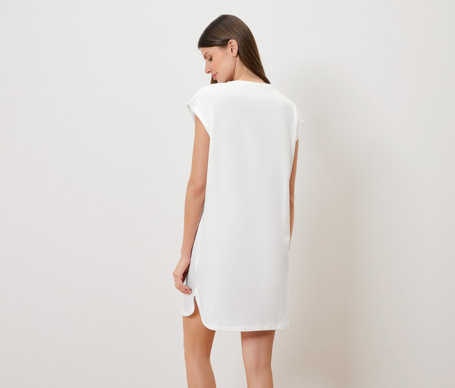 Femme vue de dos portant une chemise de nuit blanche.