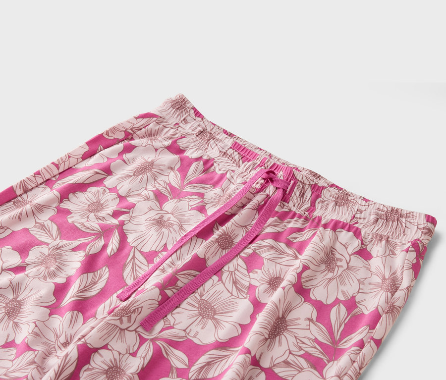 Gros plan sur un pantalon rose à motif floral avec cordon de serrage rose.