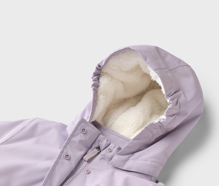 Gros plan d'une veste violette avec une capuche doublée de polaire crème. La fermeture éclair et les boutons-pression sont visibles.