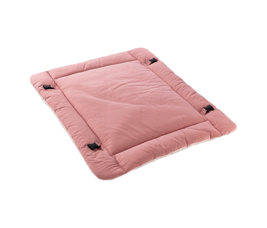 Un tapis rembourré rose rectangulaire avec une texture douce et moelleuse et des boucles noires sur les côtés, vu en angle.
