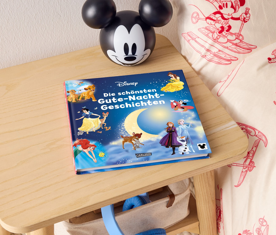 Sur une table de chevet se trouvent un livre d'histoires Disney pour le coucher et une lampe Mickey Mouse.