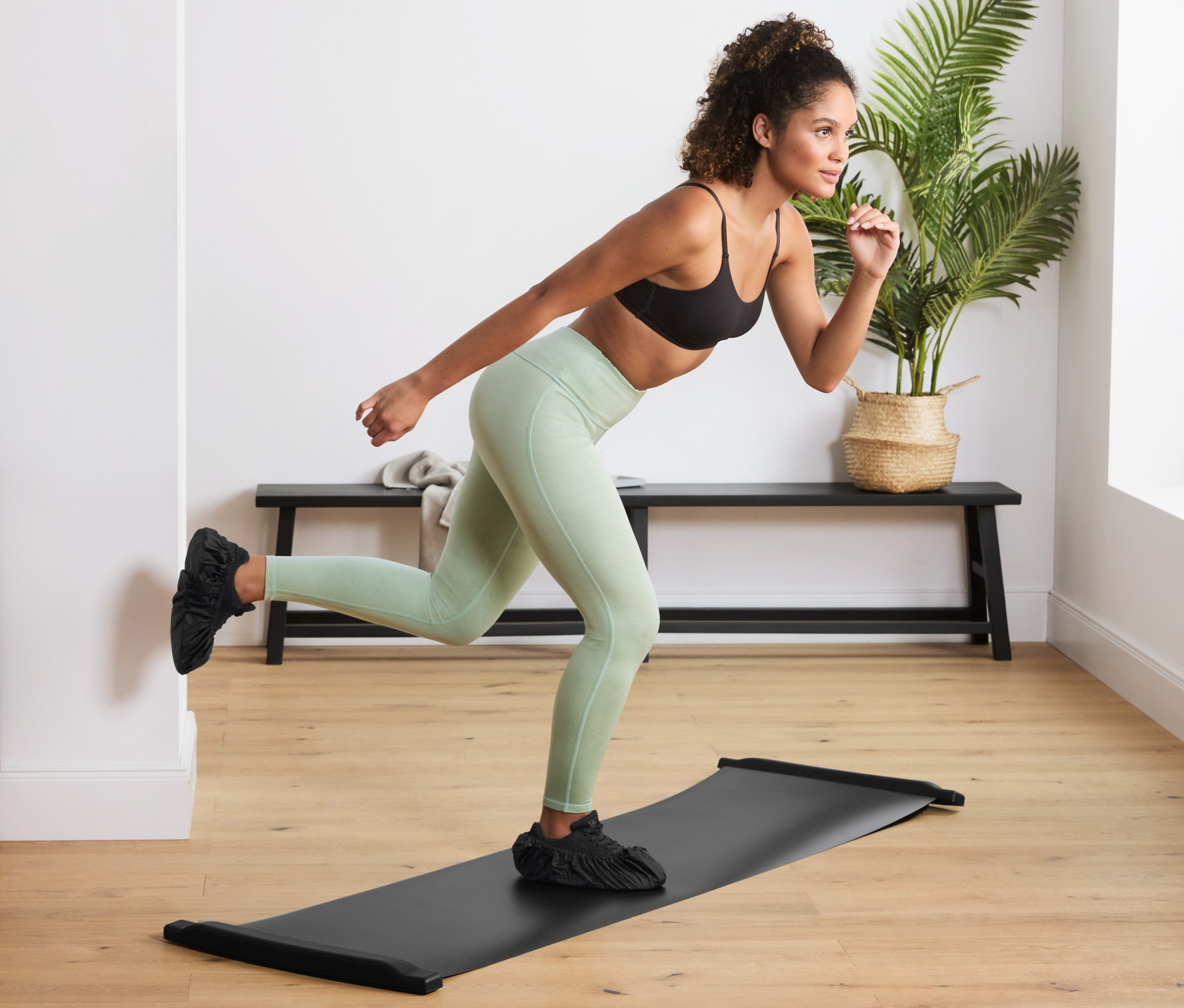 Femme faisant de l'exercice sur une planche glissante d'entraînement dans un salon.