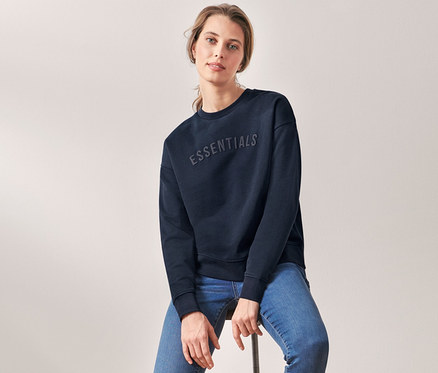 Femme assise sur un tabouret portant un sweat-shirt bleu foncé.