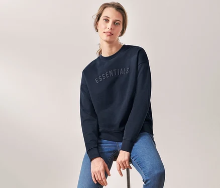 Femme assise sur un tabouret portant un sweat-shirt bleu foncé.