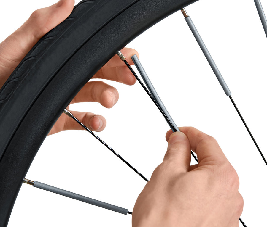 Des mains installent 36 réflecteurs de rayons sur un vélo.