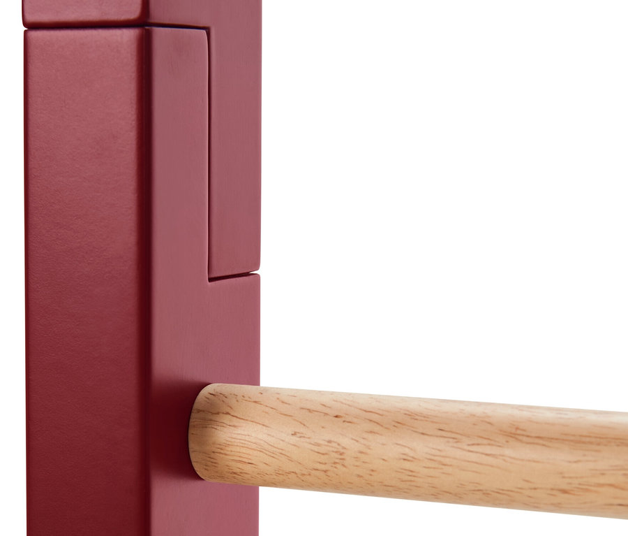 Détail d'une échelle décorative avec des éléments latéraux rouges et une barre en bois.