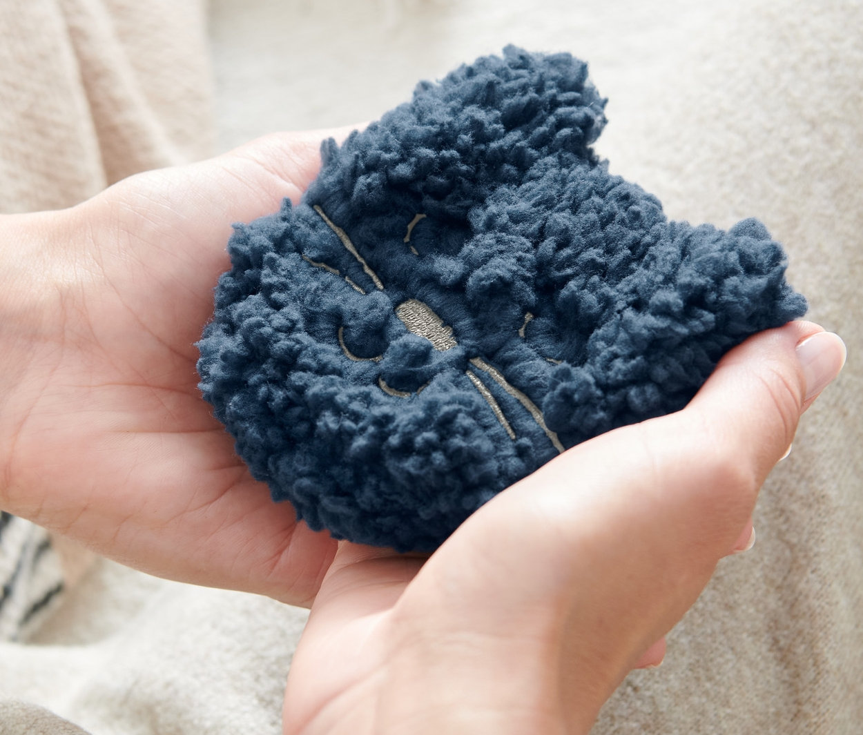 Une personne tient deux chaufferettes de poche, « chat » dans ses mains.