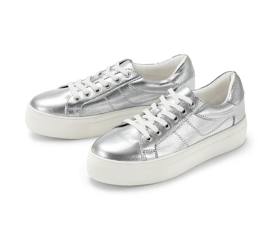 Deux sneakers à plateau en cuir argentés sont placés côte à côte sur un fond blanc.