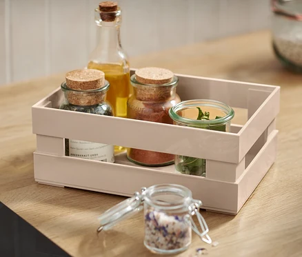 Une boîte de rangement beige avec des épices et de l'huile sur un comptoir en bois.
