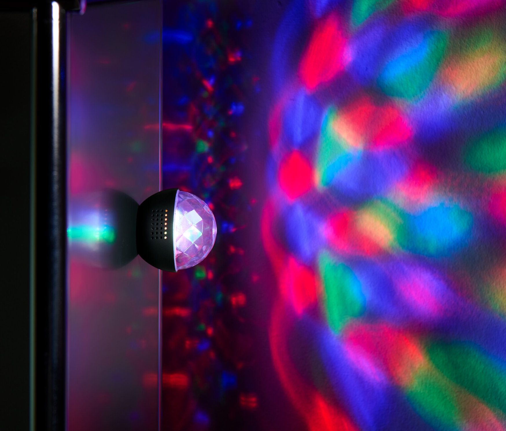 Une mini-boule disco fixée au mur projette des lumières colorées sur le mur.