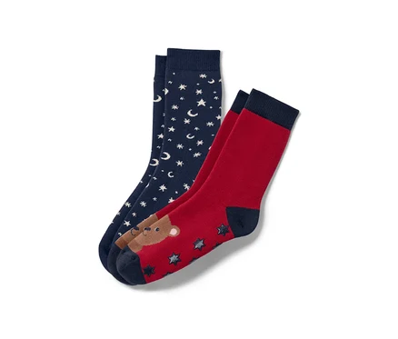 Deux paires de chaussettes antidérapantes pour enfant : une paire bleu marine avec des étoiles et des lunes blanches, une paire rouge avec un ours et des étoiles.