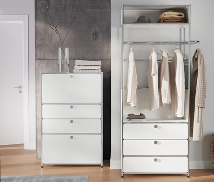 Dans la pièce, une garde-robe en métal «
CN3
» avec tringle à vêtements et 3 tiroirs et une commode en métal «
CN3
» à 2 abattants et 2 tiroirs, blanc.