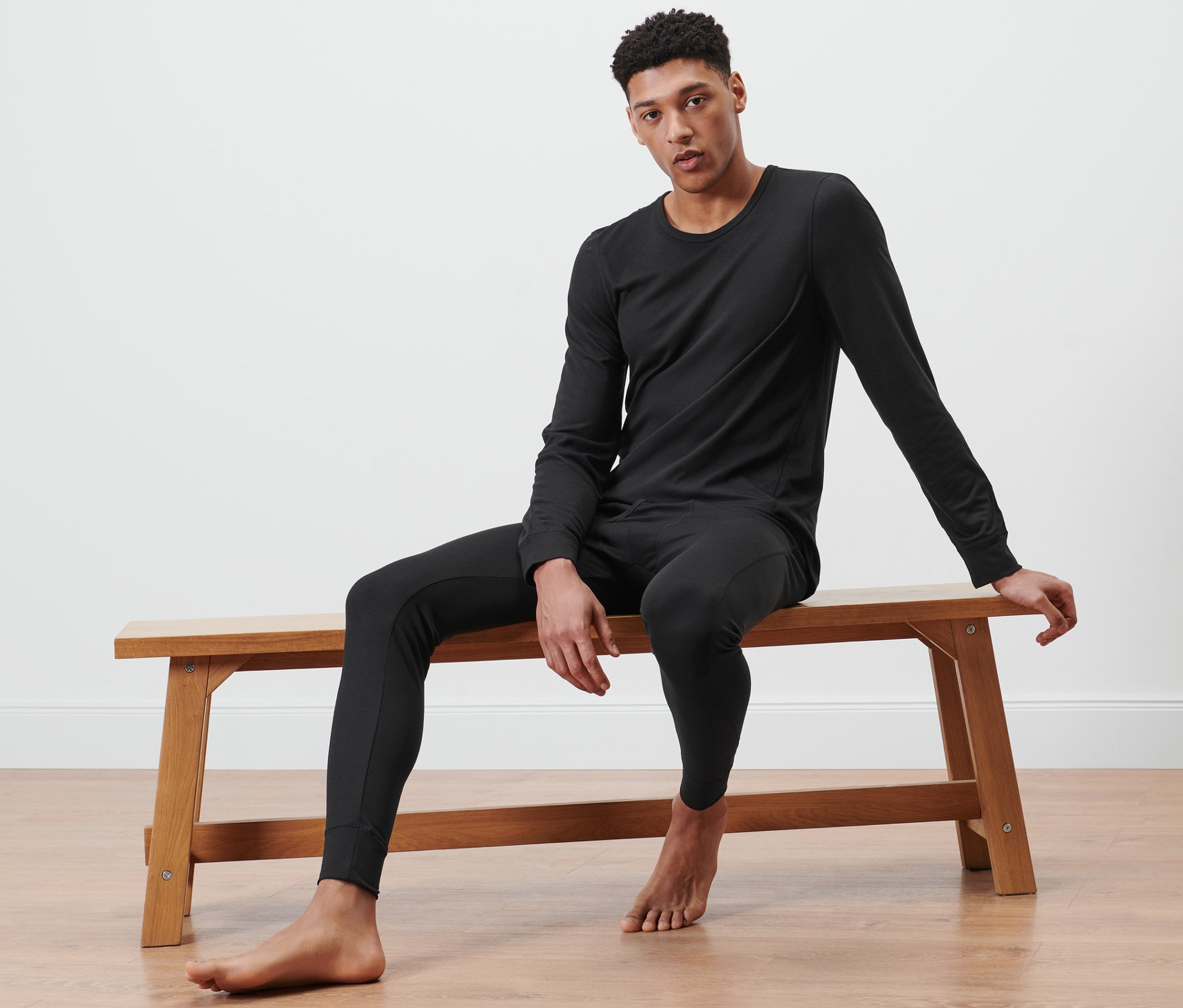 Un homme est assis sur un banc et porte des sous-vêtements fonctionnels thermiques noirs.