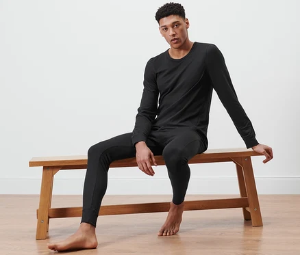 Un homme est assis sur un banc et porte des sous-vêtements fonctionnels thermiques noirs.