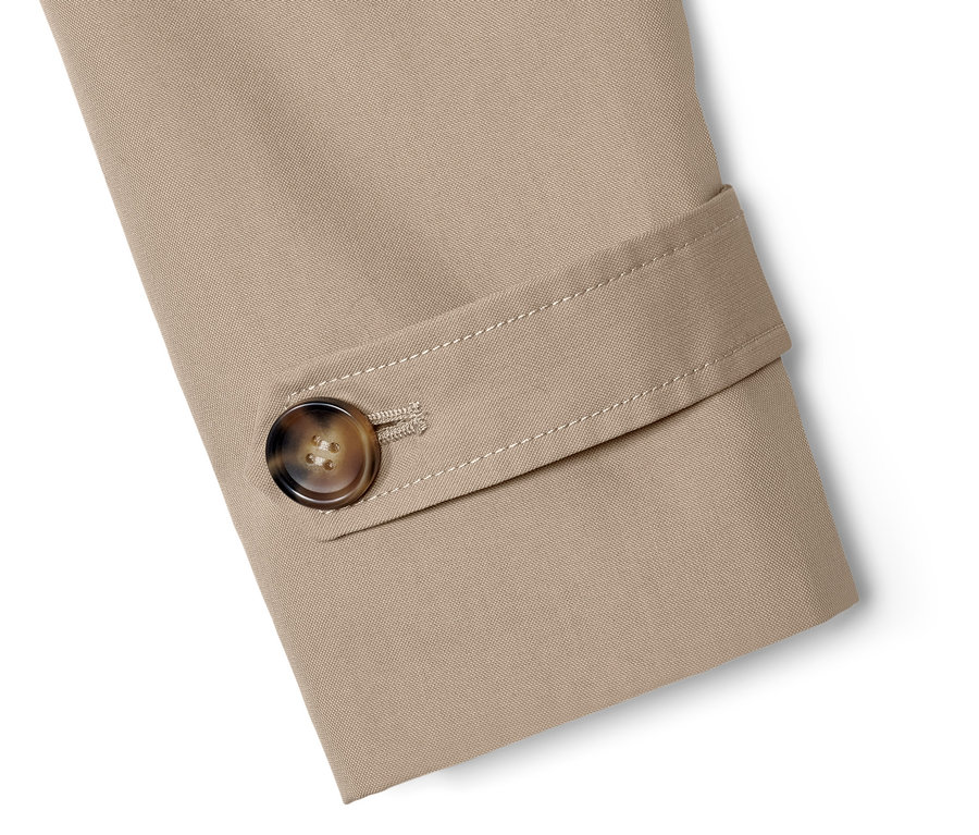 Détail d'un trench-coat beige avec un bouton marron.