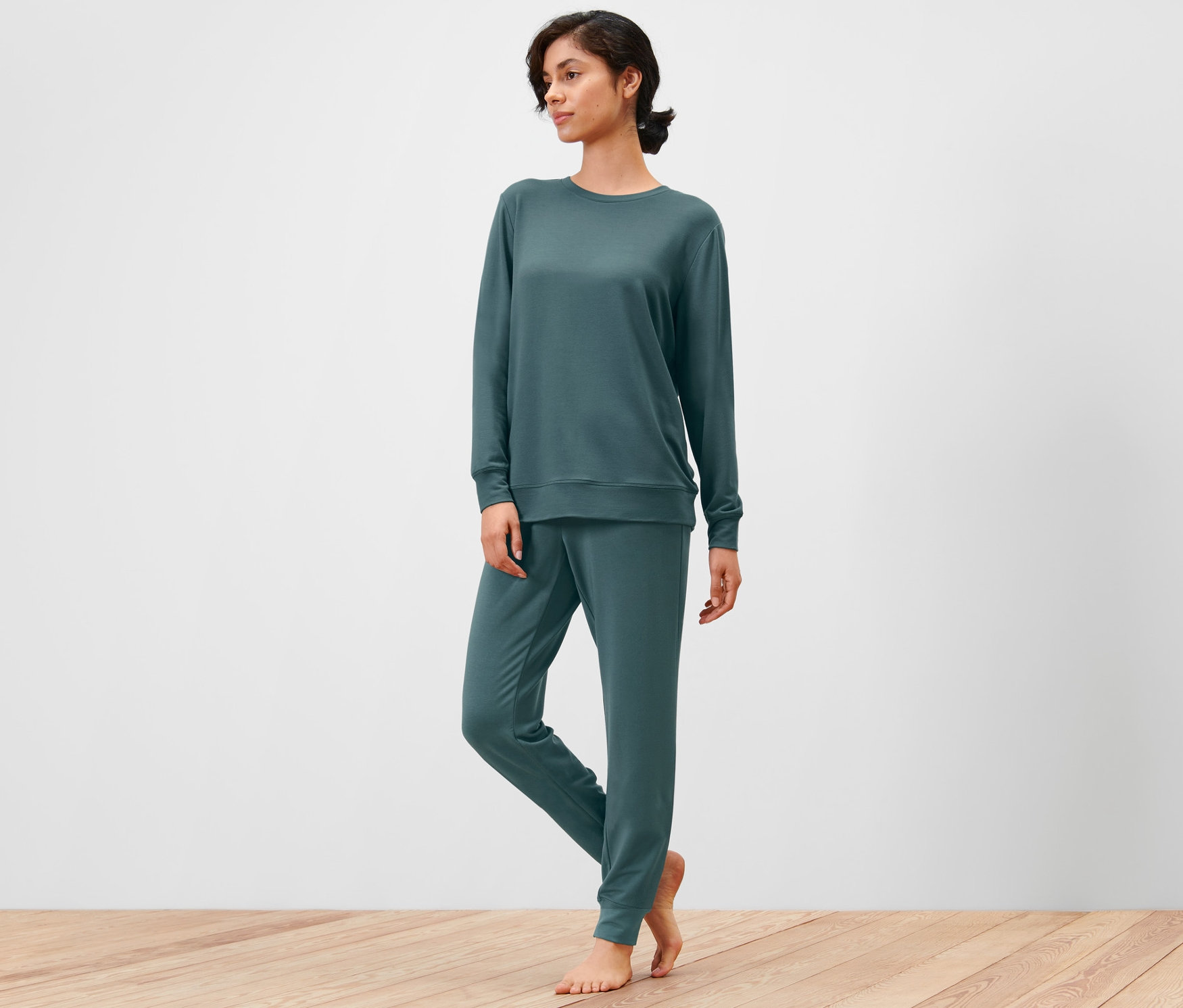 Femme en tenue d’intérieur debout sur un plancher en bois.