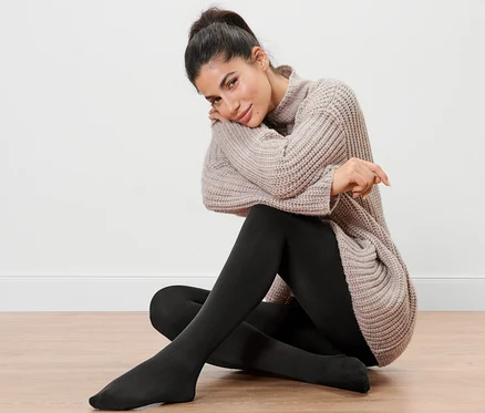Une femme est assise par terre et porte un collant thermique.