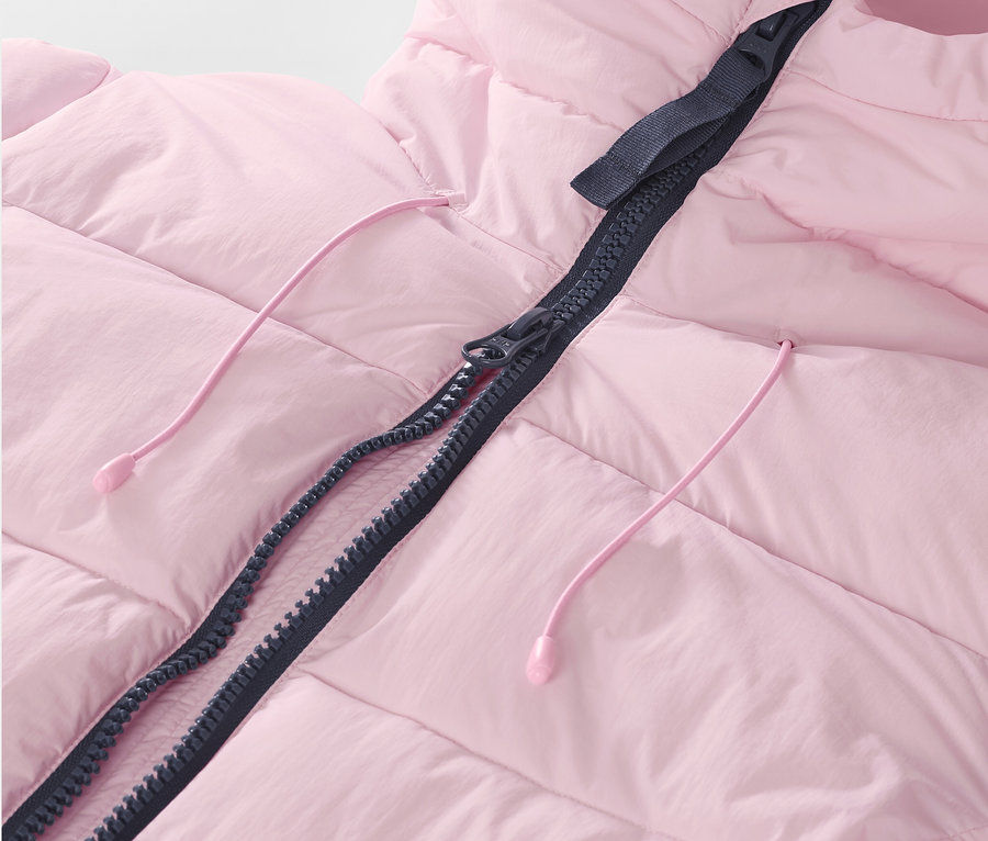 Gros plan sur une veste de ski matelassée rose avec fermeture éclair et cordons de serrage.
