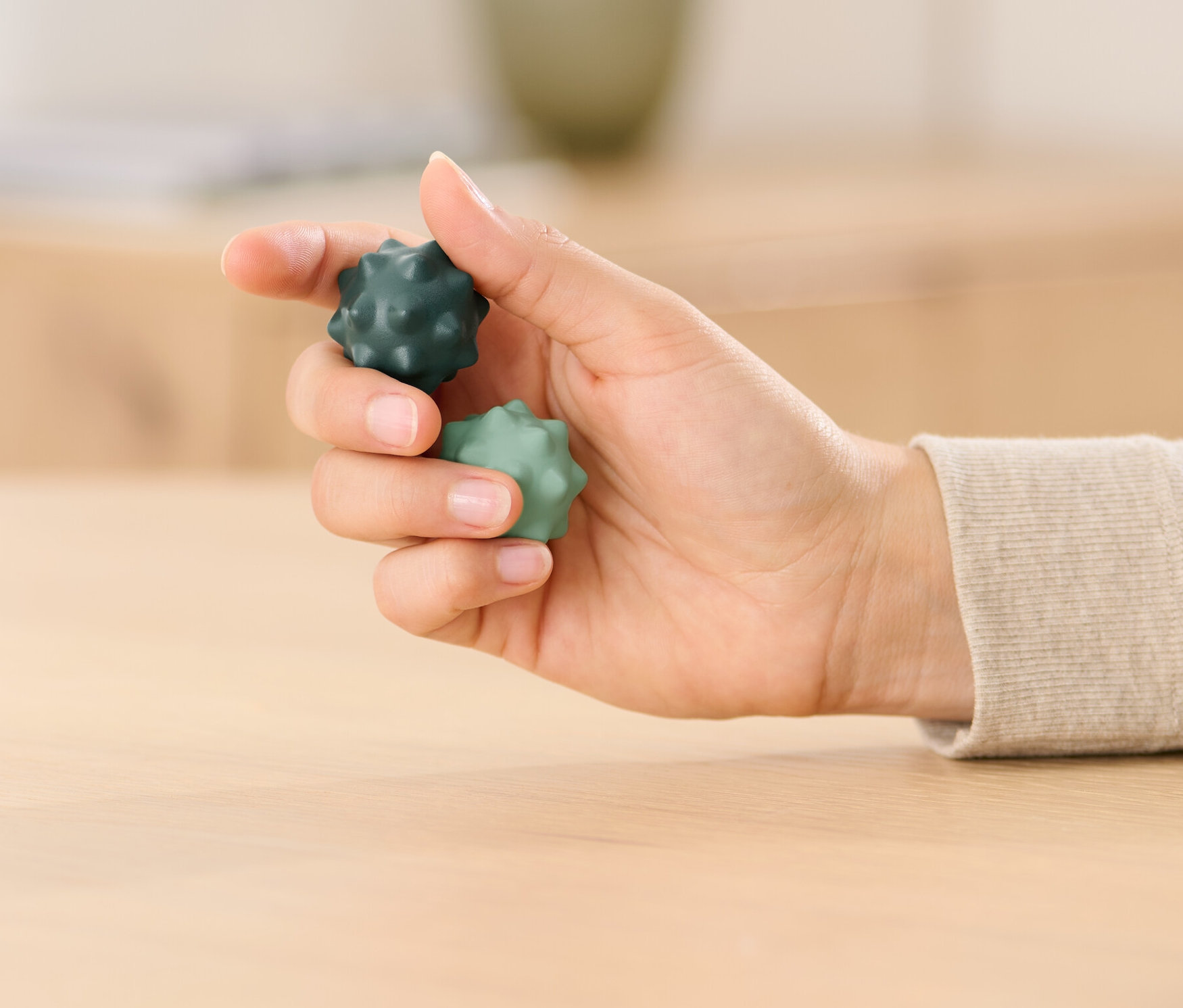 Une femme tient deux boules de gymnastique des doigts Qi-Gong dans sa main, une vert foncé et une vert clair.