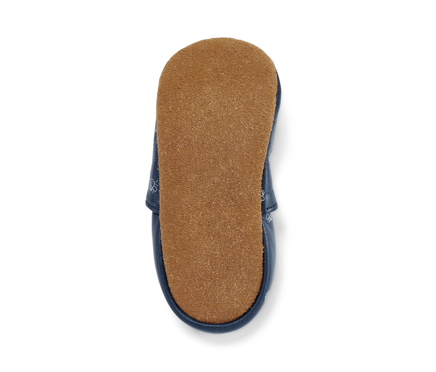 Gros plan sur des petites chaussures en cuir pour bébé avec une semelle marron.