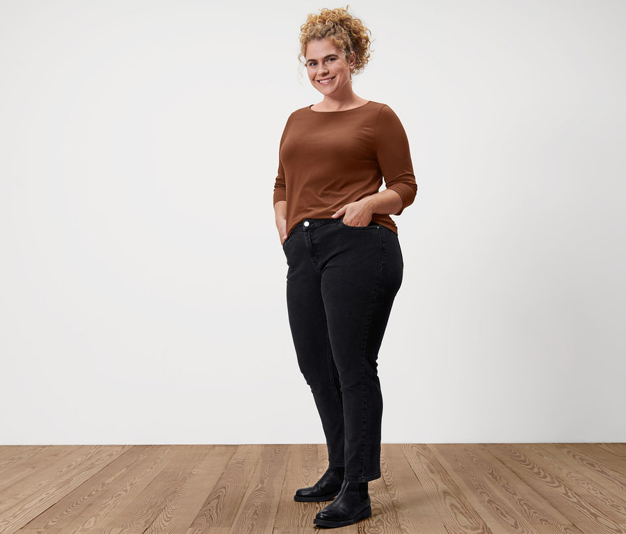 Femme posant en T-shirt manches 3/4 cognac, jean droit en denim « Fit Juna » noir et bottines en cuir.