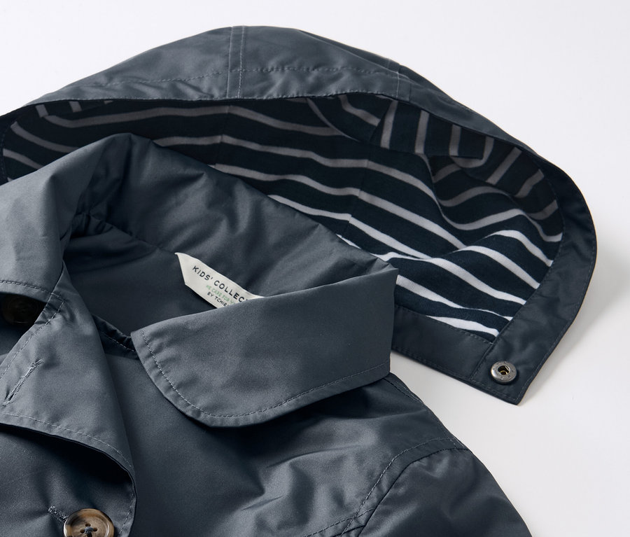 Gros plan sur un trench-coat tout-temps pour enfant avec une capuche rayée bleu et blanc.