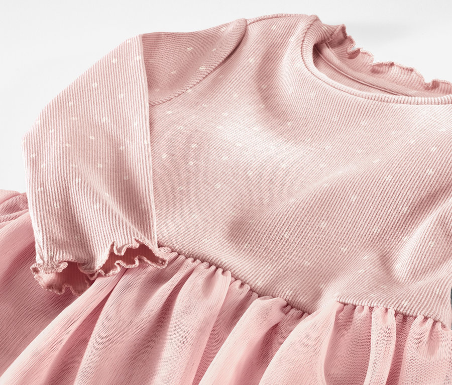 Gros plan d'une robe à côtes rose pour enfants avec des manches longues et une jupe en tulle.