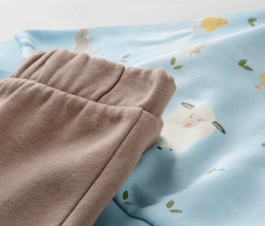 Détail d'un ensemble en sweat pour bébé avec motif agneaux et poussins.