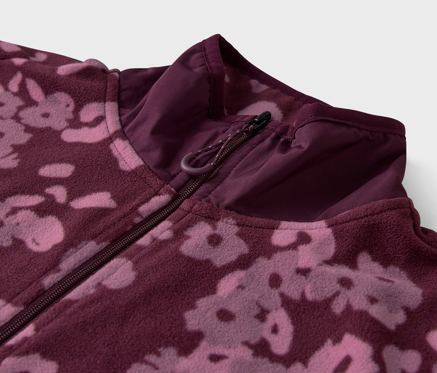 Gros plan sur une veste en polaire violette à motif floral avec une fermeture éclair.