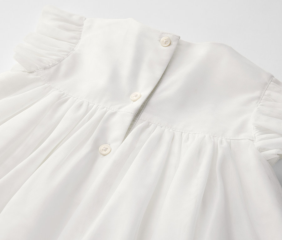 Gros plan sur une robe en tulle pour bébé avec des boutons dans le dos.