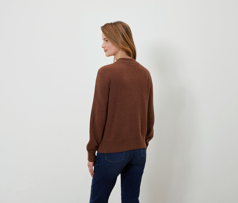 Vue arrière d'une femme aux cheveux bruns portant un pull marron et un jean bleu foncé.