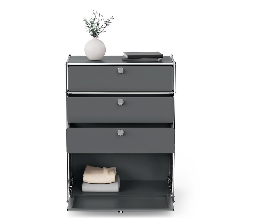 Commode grise avec trois tiroirs, dont un est ouvert, et une armoire basse avec des vêtements.