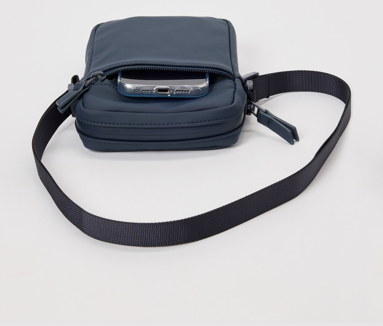 Sac à bandoulière de pluie bleu avec un téléphone dans la poche.