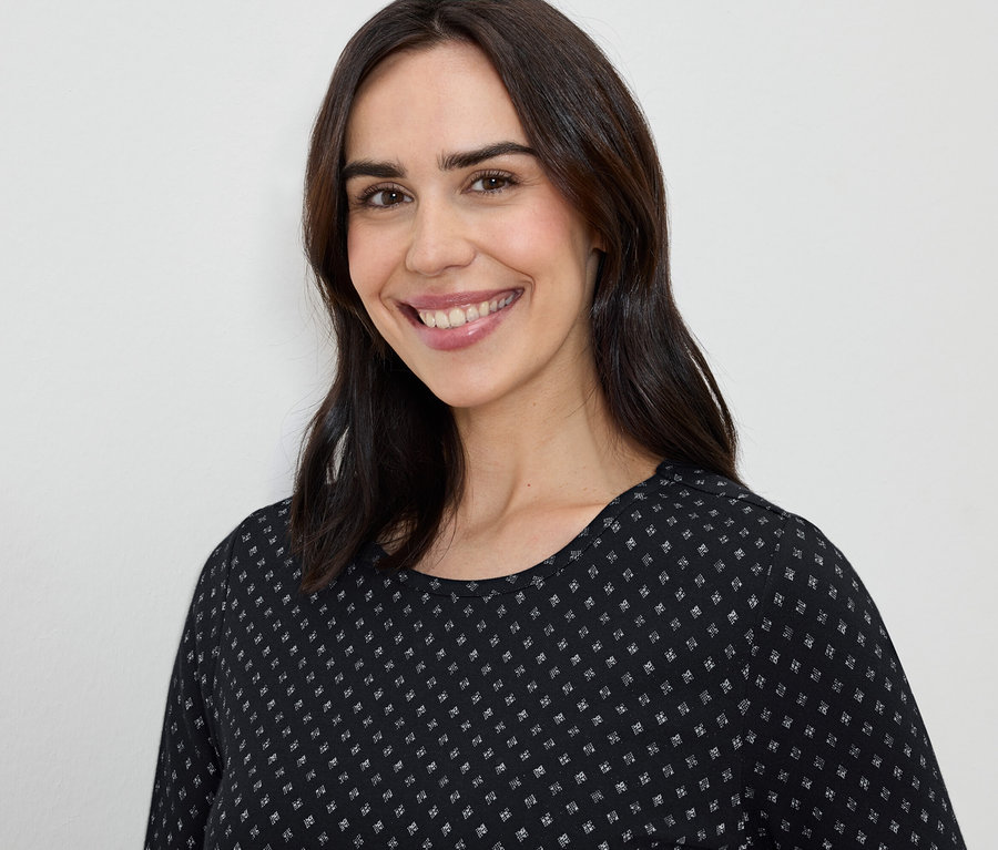 Femme souriante avec des cheveux bruns et une robe noire et blanche.