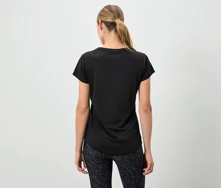 Femme vue de dos portant un t-shirt noir et un legging à motifs.