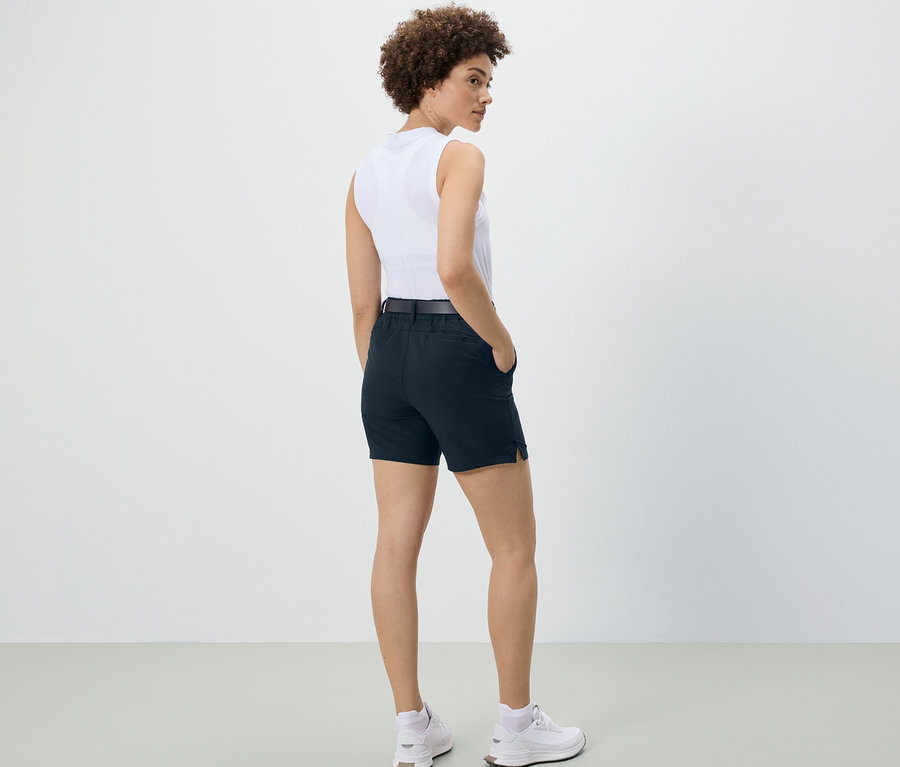 Une femme, vue de dos, porte un short technique en softshell bleu foncé.