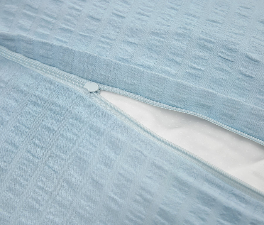 Gros plan d'une taie d'oreiller bleu clair avec fermeture éclair et intérieur blanc.