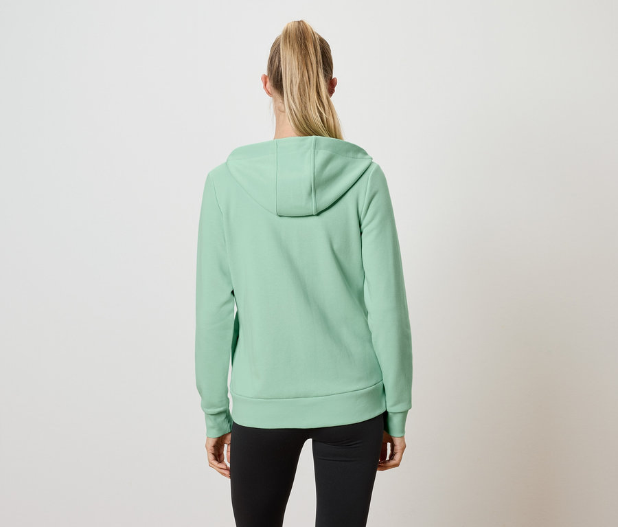 Vue de dos d'une femme aux cheveux blonds attachés en queue de cheval, portant un sweat à capuche vert clair et un legging noir.
