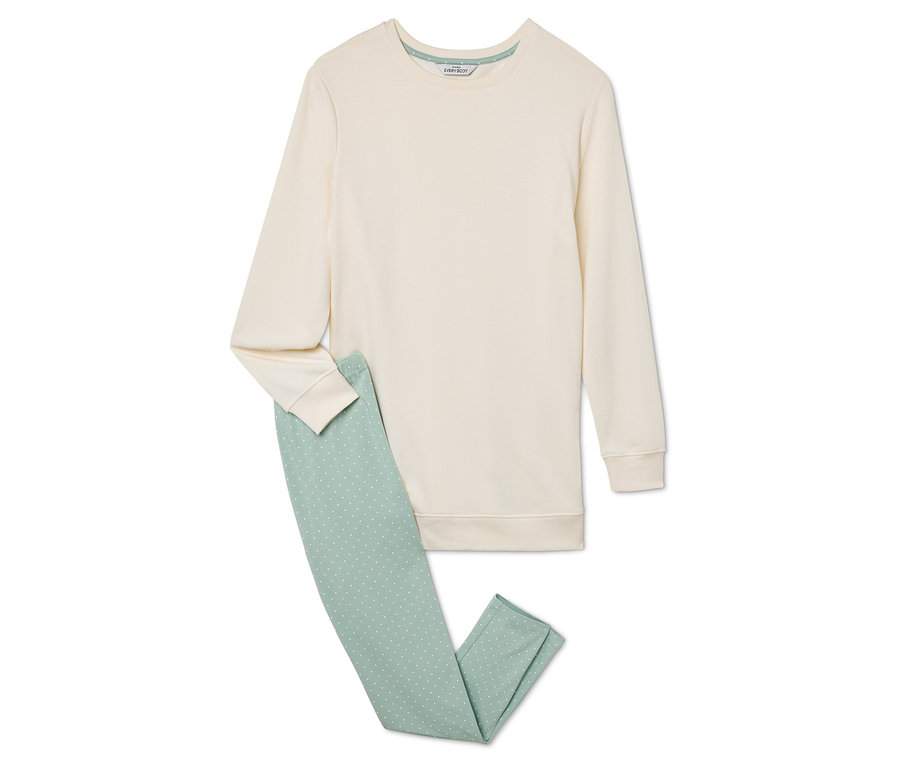 Un sweat-shirt beige et un pantalon vert clair reposent sur un fond blanc.