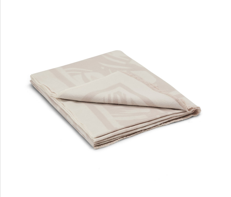 Couverture beige pliée avec un motif géométrique.