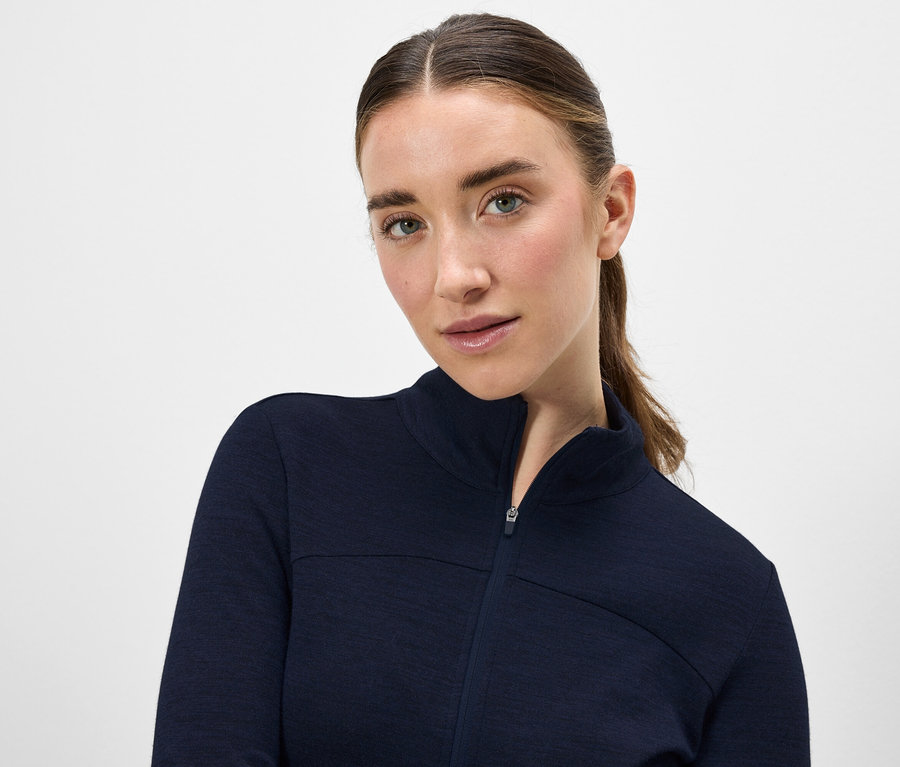 Portrait d'une femme aux cheveux bruns portant une veste bleu marine zippée.