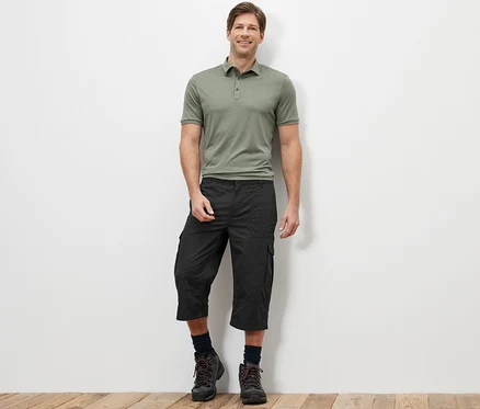 Un homme debout portant un polo vert et un bermuda cargo longueur 3/4 anthracite.