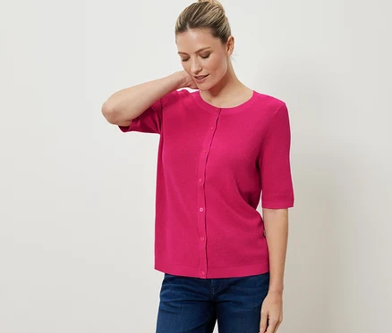 Une femme porte un cardigan rose en maille fine avec du lin et un jean.